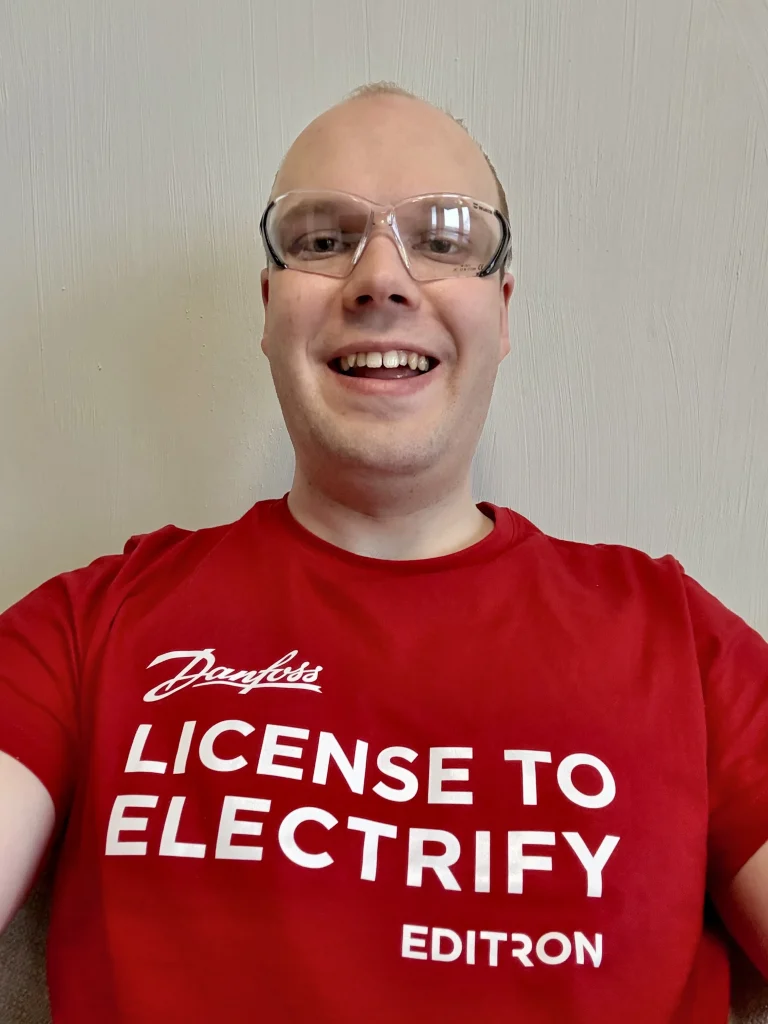 Roni punaisessa Danfoss T-paidassa, jossa lukee "License to electrify"